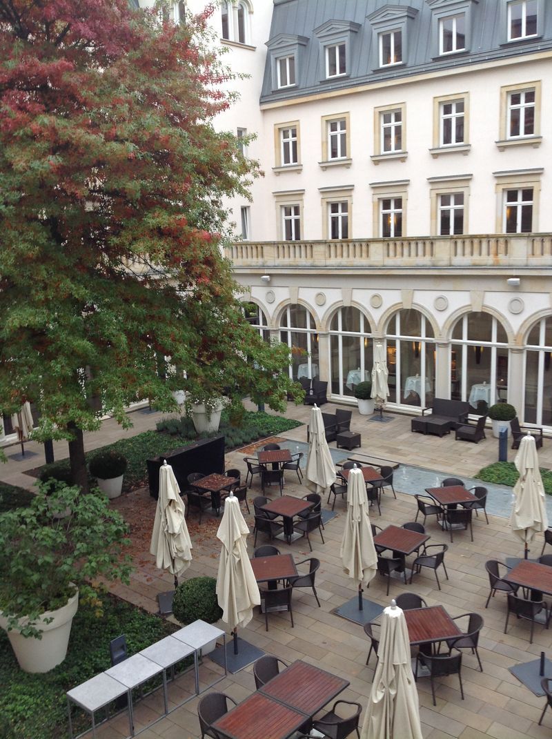 A courtyard with tables and chairs and umbrellas in front of a building