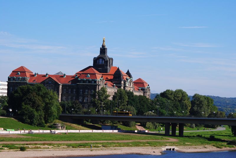 A bridge over a river with a large building in the background