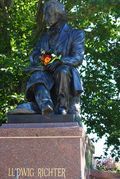 A statue of a man sitting on a pedestal holding a flower.