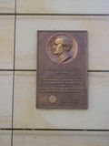 A plaque with a picture of a man on it is on a tiled wall.