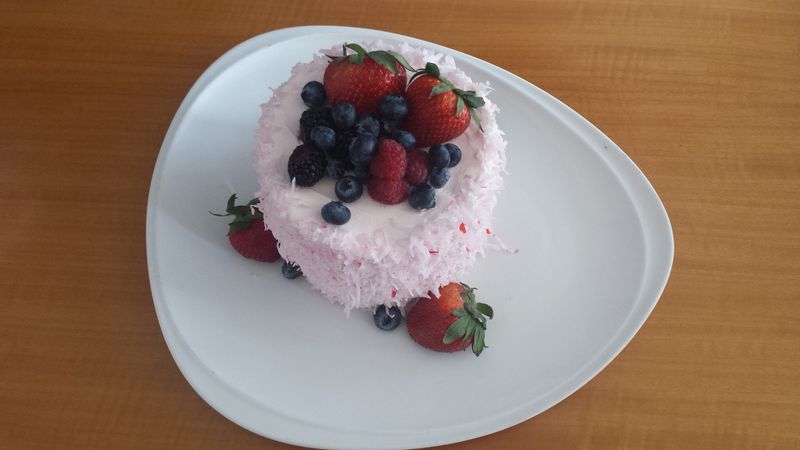 A white plate topped with a cake and berries
