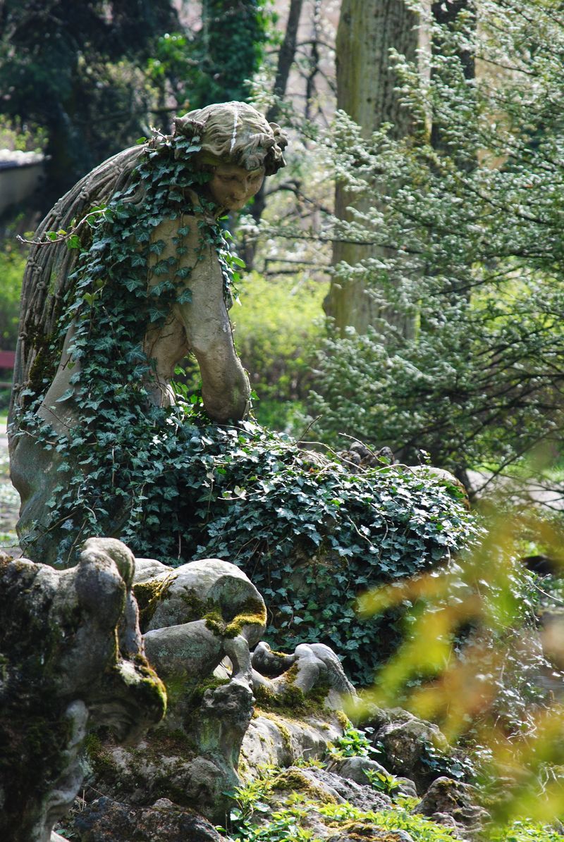 A statue of a woman covered in ivy in a garden.