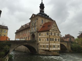 A large building is sitting on top of a bridge over a river.