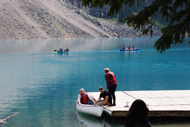 A group of people are sitting in a canoe on a dock near a lake.