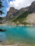 A lake surrounded by mountains and trees on a sunny day.