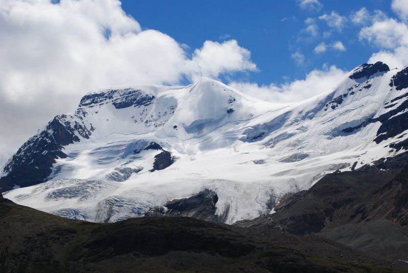 A snowy mountain with a blue sky in the background