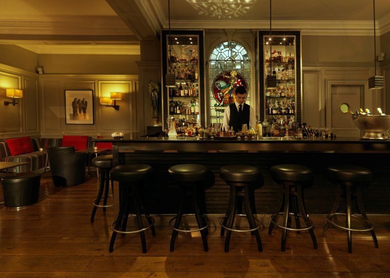 A bar with stools and a bartender standing behind it.