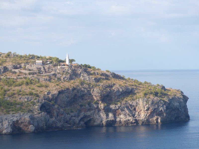 A small island in the middle of the ocean with a lighthouse on top of it.