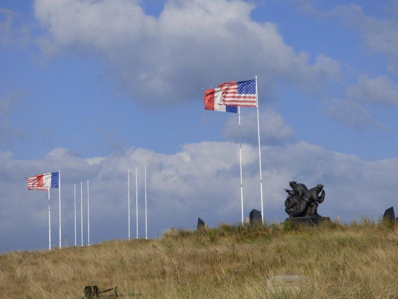A bunch of flags are flying in the wind on a hill