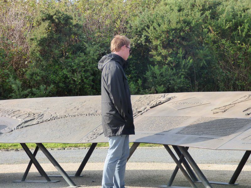 A man in a black jacket stands in front of a table