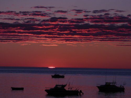 A sunset over the ocean with boats in the water