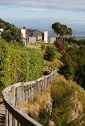 A wooden walkway going up a hill with a house in the background.