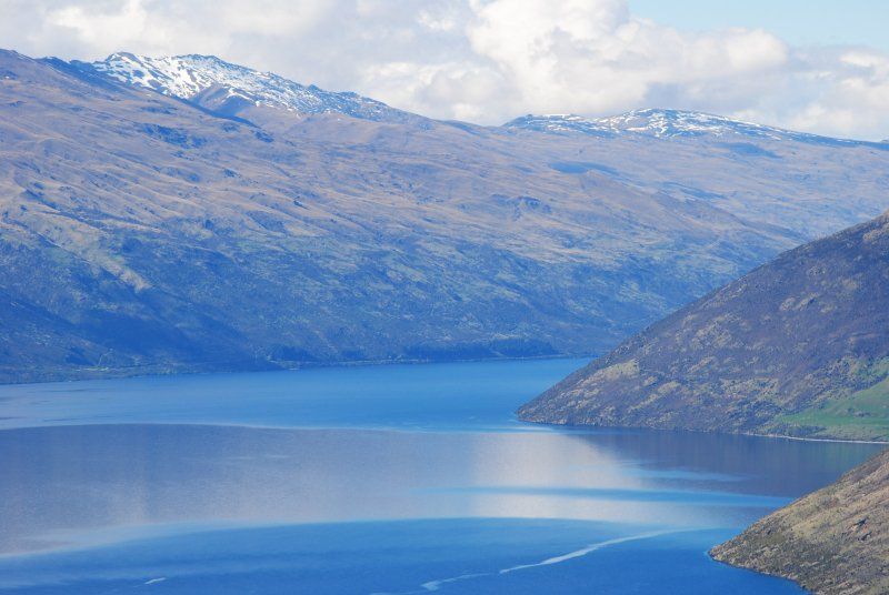 A large body of water surrounded by mountains on a sunny day.