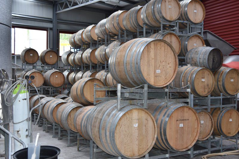 A warehouse filled with lots of wooden barrels stacked on top of each other.