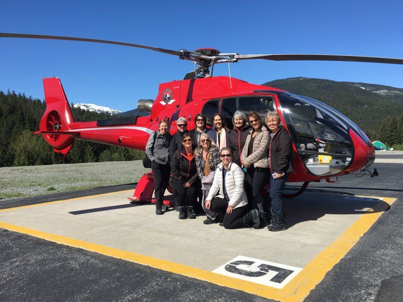 A group of people are posing for a picture in front of a red helicopter.