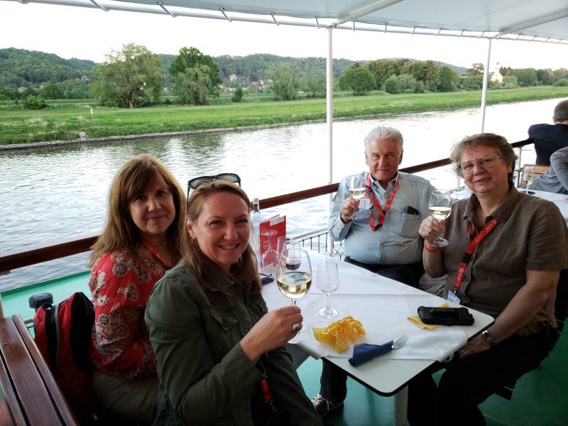 A group of people are sitting at a table on a boat drinking wine