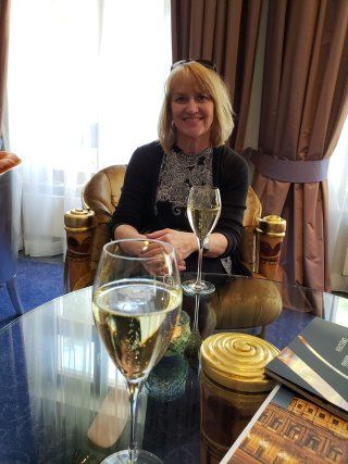 A woman is sitting at a table with two glasses of champagne.