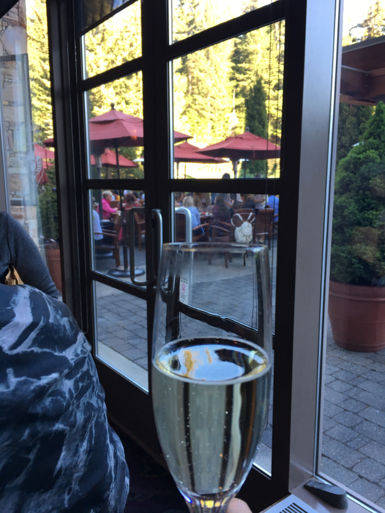 A person is holding a glass of champagne in front of a window