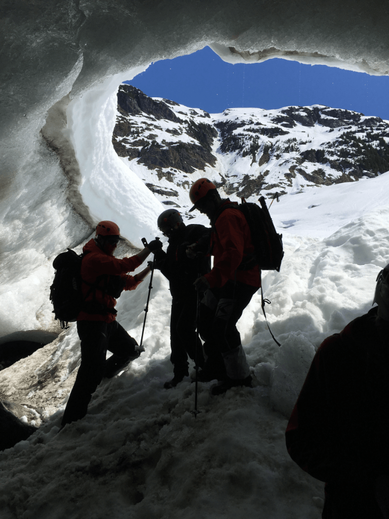 A group of people are walking through a cave in the snow