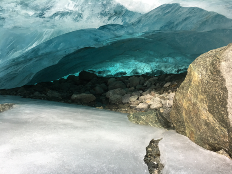 A cave in the snow with mountains in the background