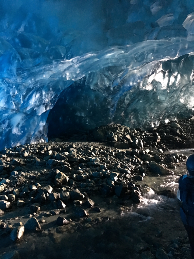 A person is standing inside of an ice cave
