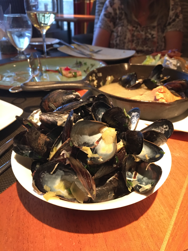 A plate of mussels is sitting on a wooden table.