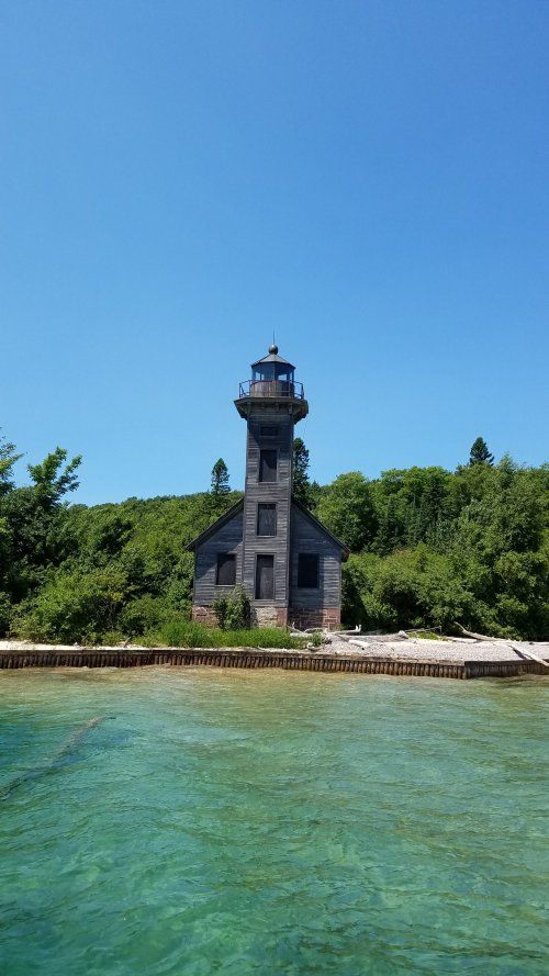A lighthouse is sitting on top of a small island in the middle of a body of water.