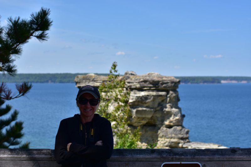 A woman is standing on a ledge overlooking a body of water.