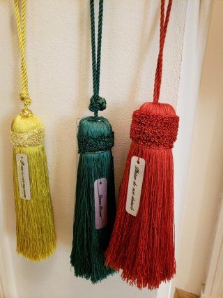Three tassels of different colors are hanging on a white wall