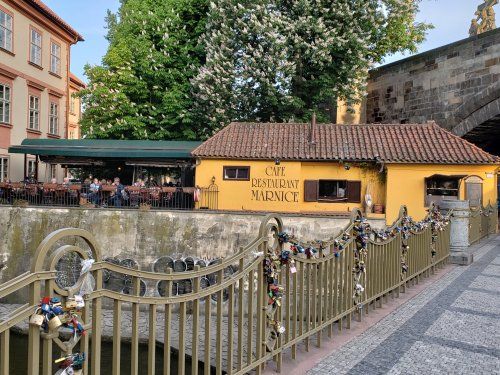 A yellow building with a red tile roof is behind a fence with padlocks attached to it.