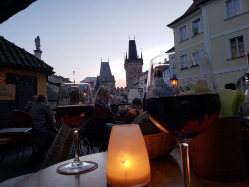 Two glasses of wine and a candle on a table with a city in the background.