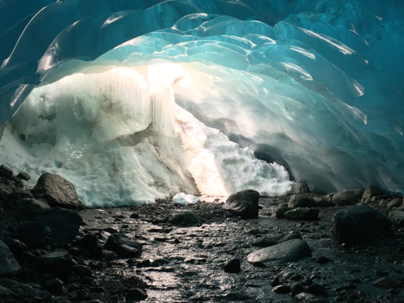 A large ice cave with a river coming out of it