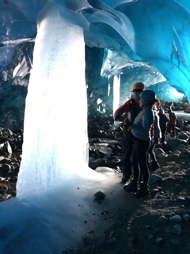 A group of people are standing inside of an ice cave