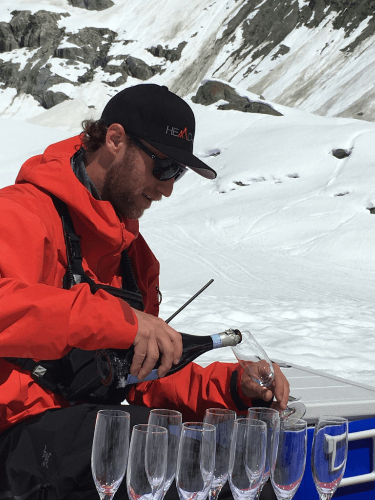 A man in a red jacket is pouring champagne into glasses