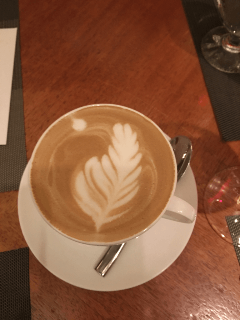 A cup of cappuccino with a leaf design on the foam