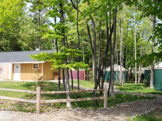 A house with a wooden fence in front of it surrounded by trees.