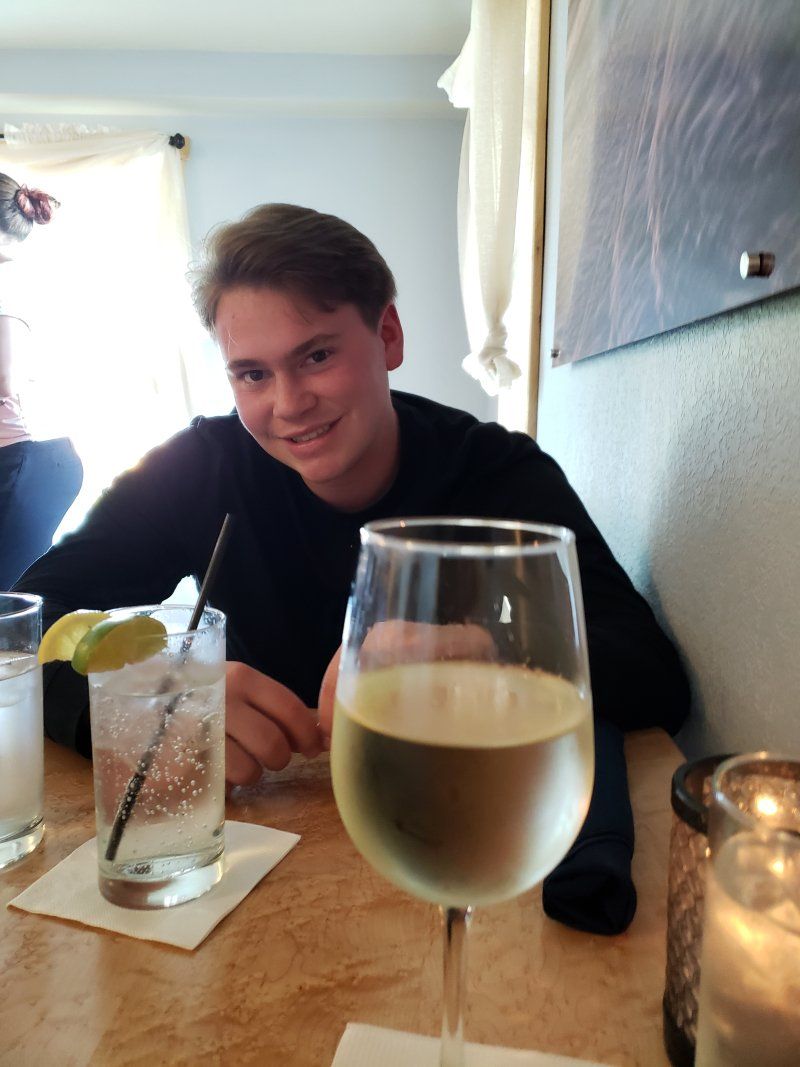 A man sits at a table with a glass of wine