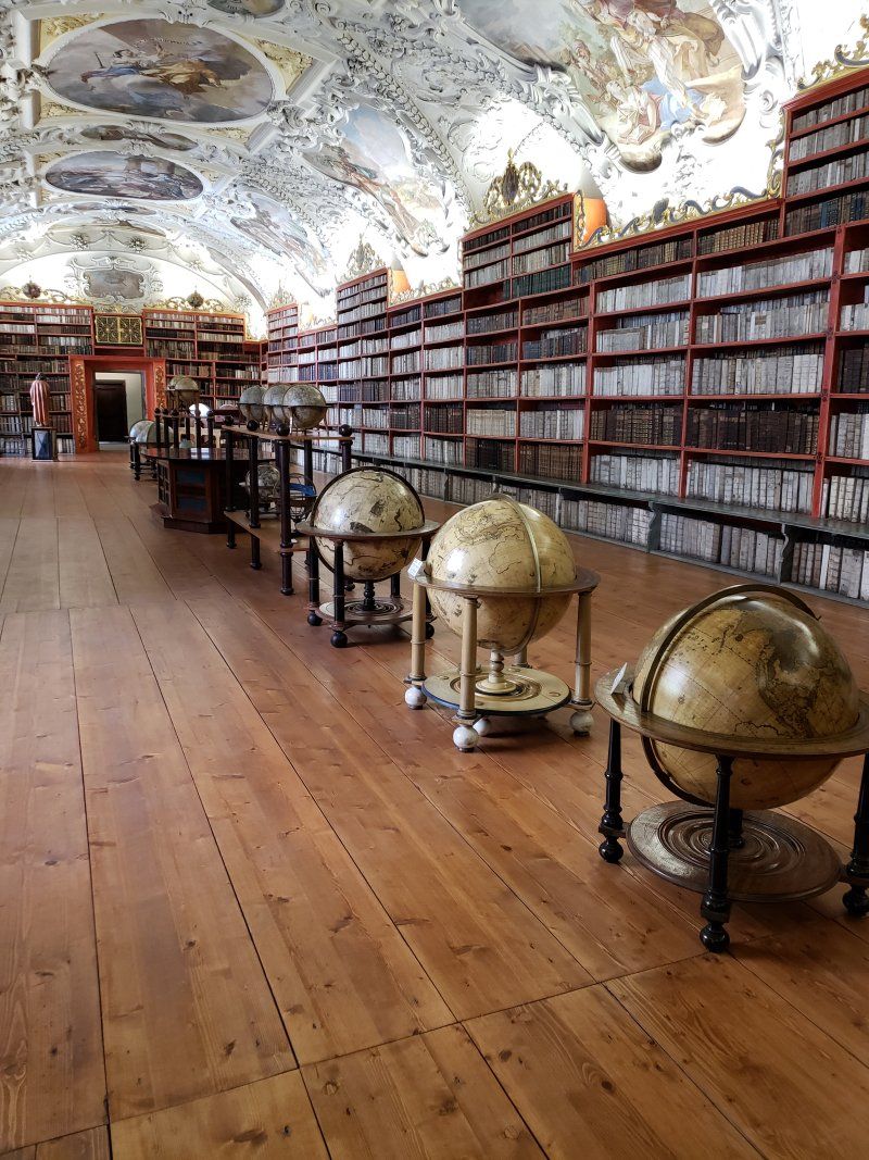 A library filled with lots of books and globe displays.