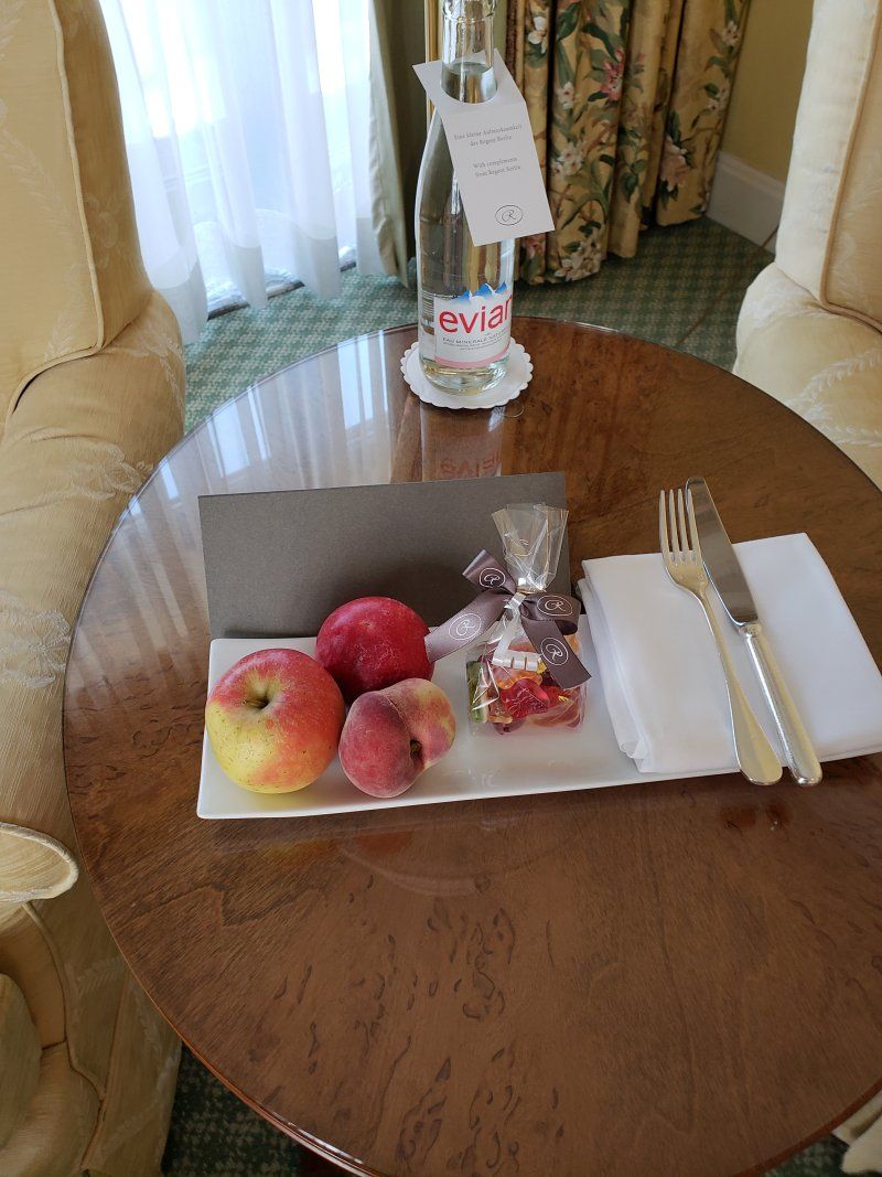 A table with a tray of fruit and a bottle of evian water on it.