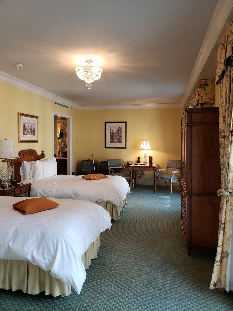 A hotel room with two beds , a desk and chairs.