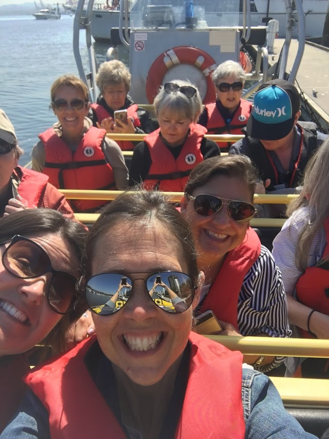 A group of people are sitting on a boat wearing life vests and sunglasses
