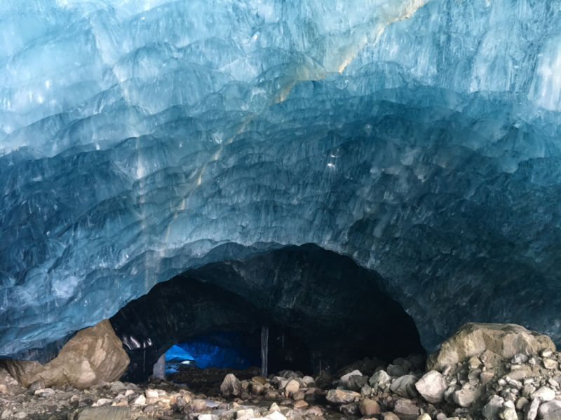 A person is standing in the entrance of an ice cave.