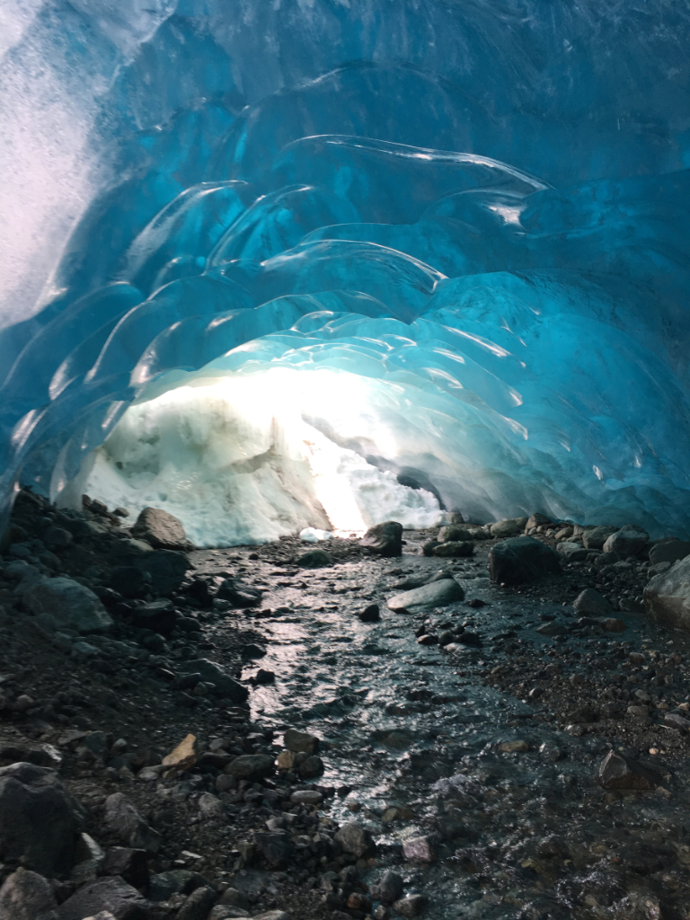 The inside of an ice cave with a river running through it.
