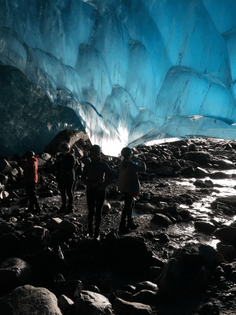 A group of people are standing inside of an ice cave.