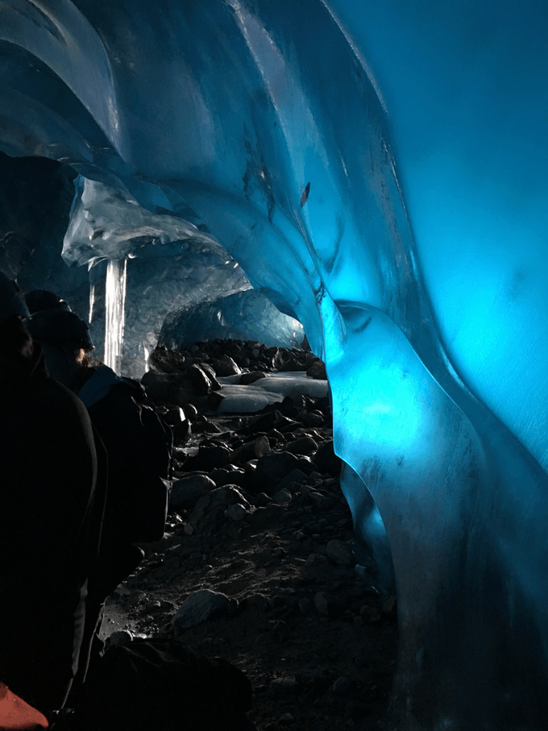 A group of people are standing inside of an ice cave.