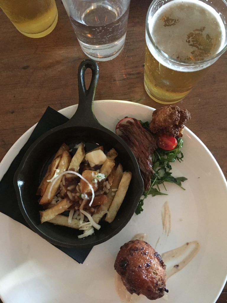 A plate of food on a table with a glass of beer