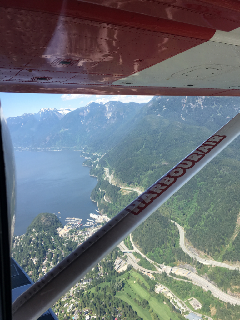 A plane is flying over a lake with mountains in the background.
