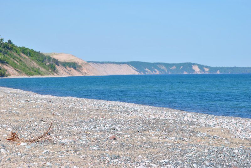 A beach with a large body of water and a cliff in the background.