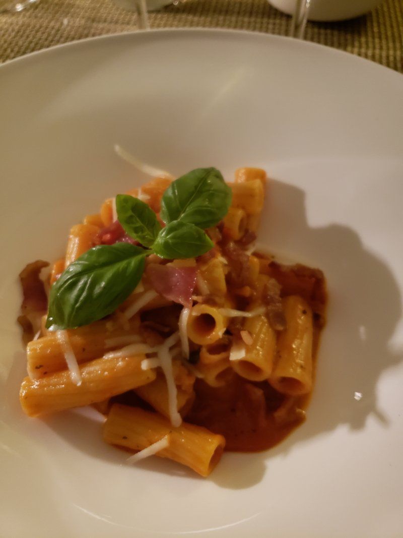 A white plate topped with pasta and basil on a table.