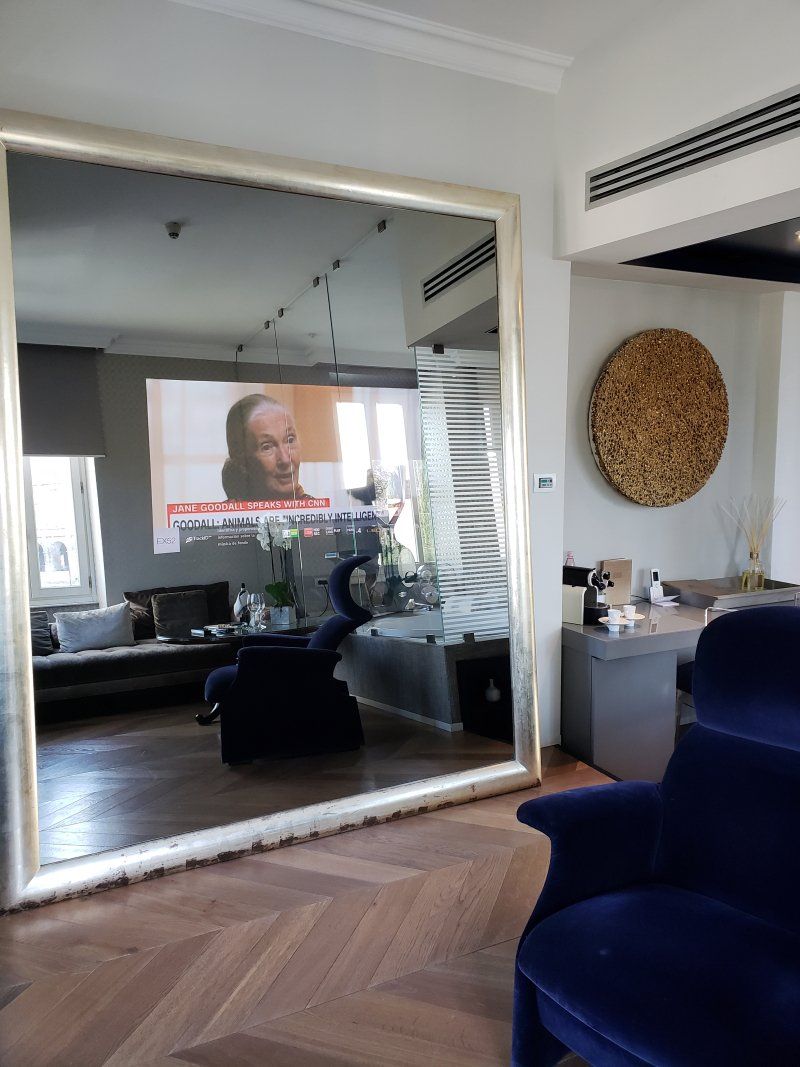A living room with a large mirror and a television on the wall.